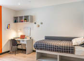 Thumbnail 3 of 16 - a small bedroom with a bed and a desk with a computer