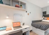 Thumbnail 2 of 16 - a bedroom with a bed and a desk with a laptop