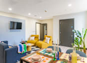 Thumbnail 6 of 16 - a living room with yellow couches and a table and a television