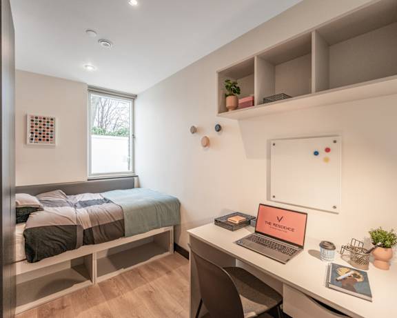 a bedroom with a bed and a desk with a laptop