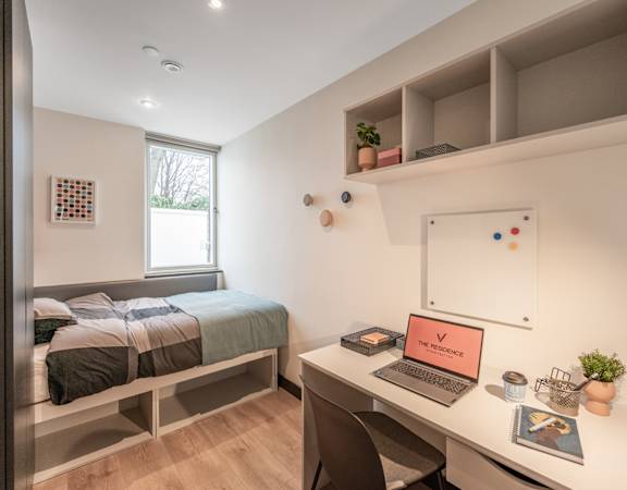 a bedroom with a bed and a desk with a laptop