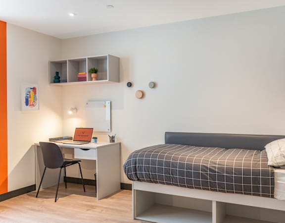 a small bedroom with a bed and a desk with a computer