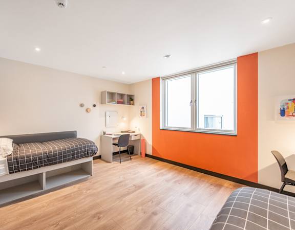 a bedroom with a bed and a desk and a window