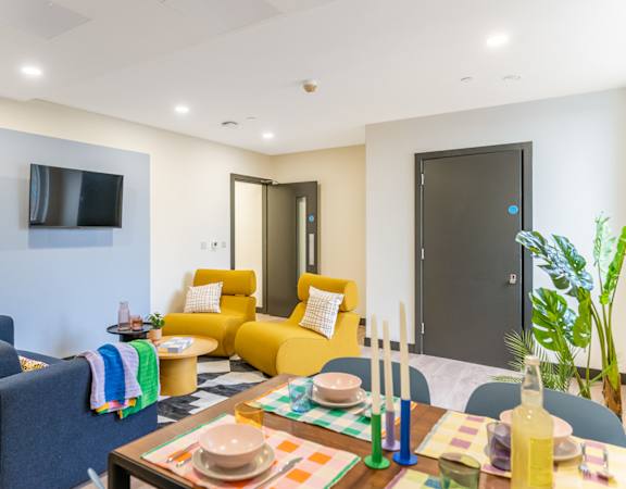 a living room with yellow couches and a table and a television
