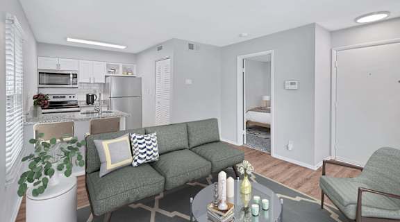 a living area with a couch coffee table and chairs and a kitchen in the background