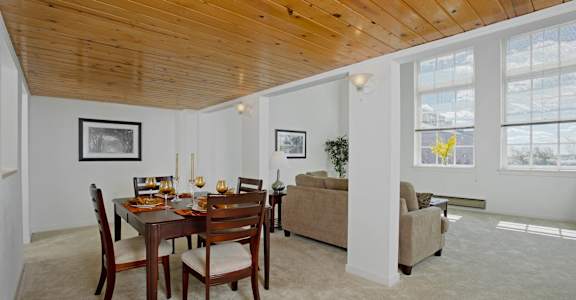 a dining room and living room with a wooden ceiling and a table and chairs at Tindeco Wharf, Baltimore