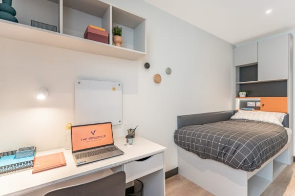 a bedroom with a bed and a desk with a laptop