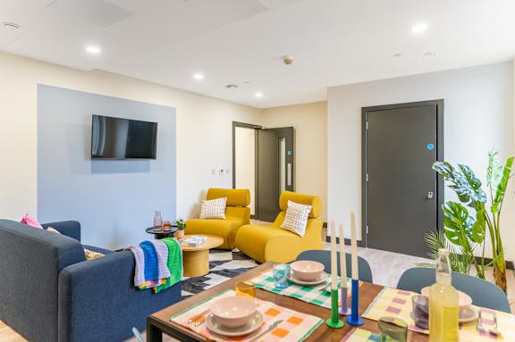 a living room with yellow couches and a table and a television