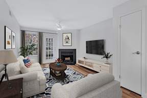 A living room with a fireplace, a couch, a chair, a coffee table, and a television.