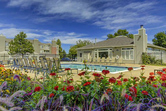 a swimming pool with chaise lounge chairs and colorful flowers in the foreground
