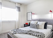 Thumbnail 4 of 7 - A bedroom with a bed covered in a black and white patterned comforter.
