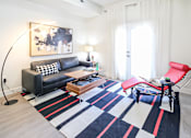 Thumbnail 3 of 7 - A black and white sofa with a red chair in front of a white door.