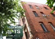 Thumbnail 29 of 29 - Upshot of large brick building in Pasadena CA. Two large signs saying "Brookmore apts" and "Brookmore Apartments" on building with green trees in front.