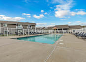 Thumbnail 1 of 10 - A large swimming pool surrounded by lounge chairs and apartment buildings.