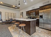 Thumbnail 6 of 10 - A modern kitchen with a bar area and stools.