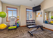 Thumbnail 5 of 9 - A gym room with a bench, weights, and exercise balls.