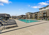 Thumbnail 8 of 10 - A swimming pool surrounded by sun loungers and apartment buildings.
