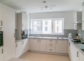 Thumbnail 5 of 8 - an empty kitchen with white cabinets and a window