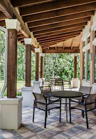 A patio with a table and chairs under a wooden roof.
