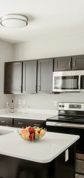 a kitchen with black cabinets and white counter tops and a stainless steel refrigerator