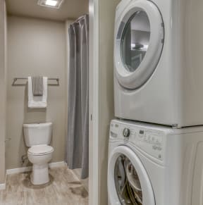 a washer and dryer in a bathroom with a toilet and a shower