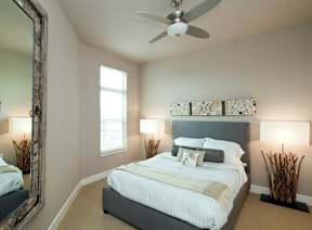 A bedroom with a large bed and a ceiling fan.