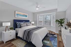 A bedroom with a bed, nightstand, and a painting on the wall.