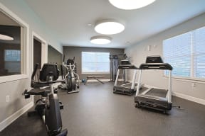 a gym with treadmills and other exercise equipment in a room with windows