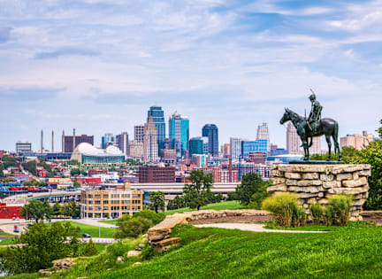 A statue of a man on a horse is in the foreground of a city skyline.