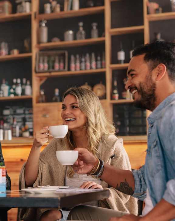 Four people are having a conversation over coffee in a cozy café setting.
