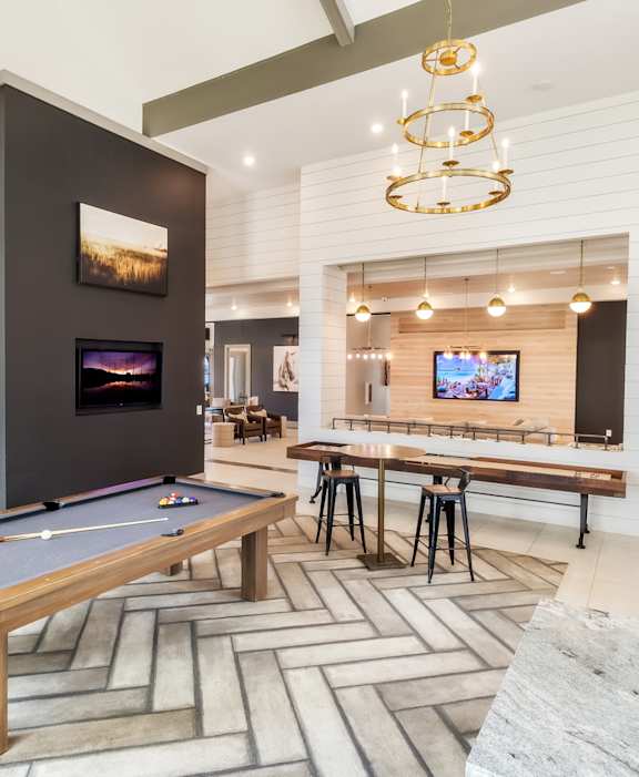 A room with a pool table and a bar area.
