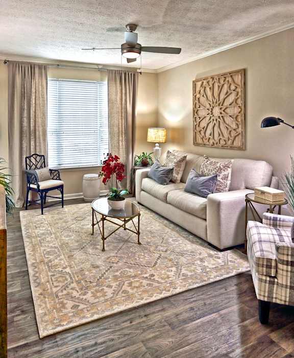 A living room with a couch, chairs, and a rug.