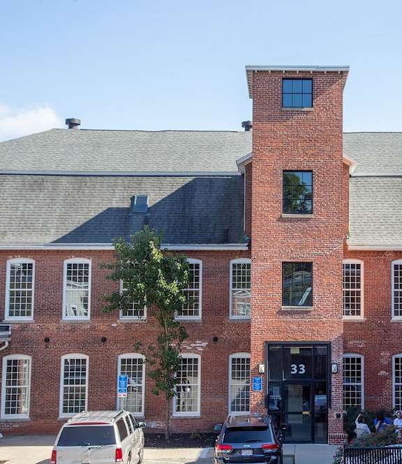 A red brick building with a black door and a black fence.