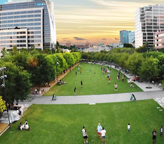 A park with people playing soccer and walking around.