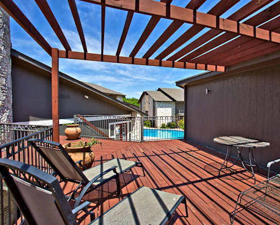 A patio with a table and chairs and a pool in the background.
