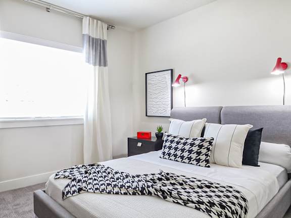 A bedroom with a bed covered in a black and white patterned comforter.