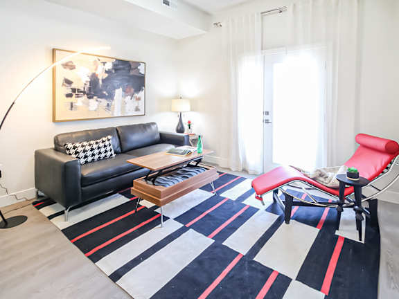 A black and white sofa with a red chair in front of a white door.
