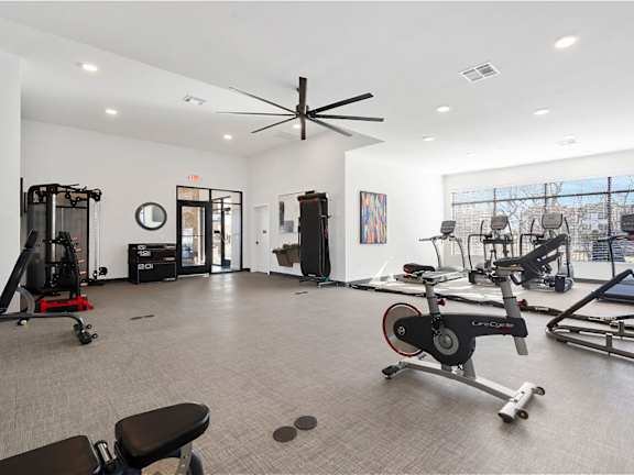 A gym with a variety of exercise equipment including a treadmill, a stationary bike, and a rowing machine.