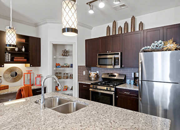 Kitchen with stainless steel appliances and pantry at Atley on the Greenway Apartments in Ashburn, VA