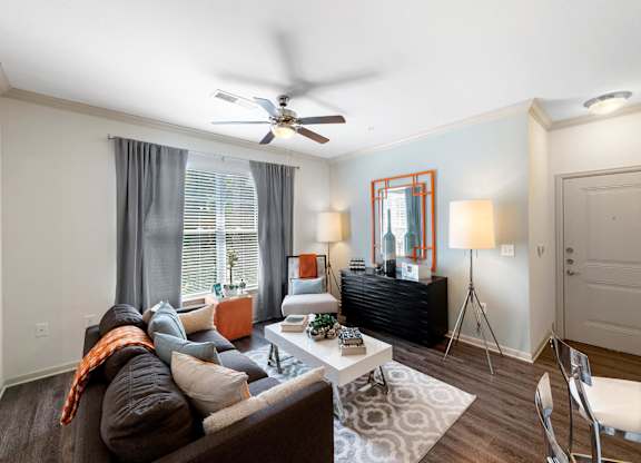 Living room with ceiling fan and large window at Atley on the Greenway Apartments in Ashburn VA