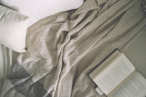 a book laying on a bed next to a blanket