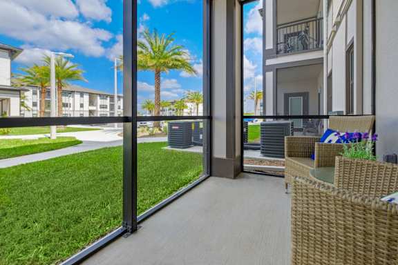 A patio with a wicker chair and table is shown through a sliding glass door.