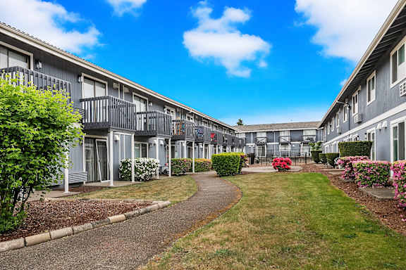 A row of grey apartment buildings with a walkway in the middle.