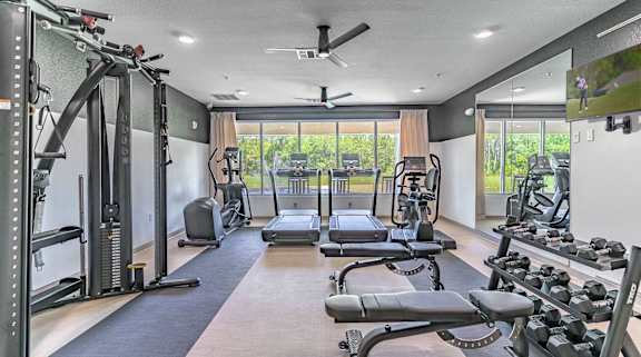 A spacious gym with a variety of equipment including treadmills, weights, and a bench press.