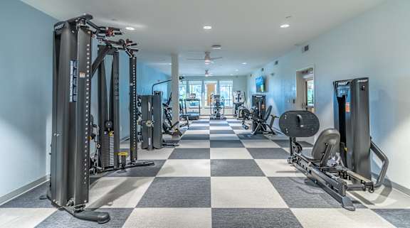 A spacious gym with a variety of equipment and a checkered floor.