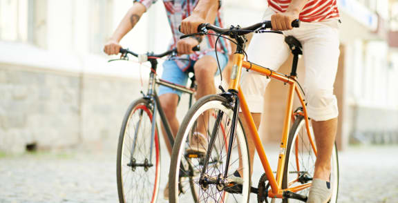 two people riding a bike on a cobblestone street