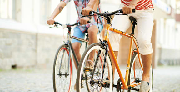 Two people riding a tan bicycle on a cobblestone street.