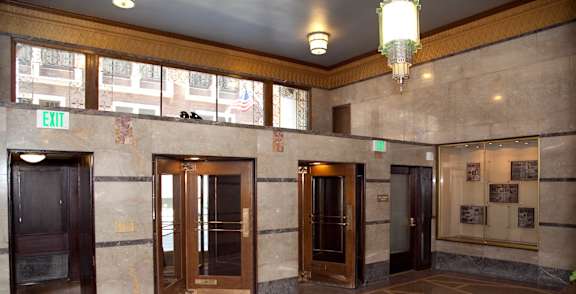 A hallway with marble floors and wooden doors.