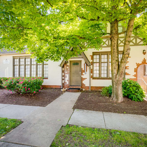 the front of a brick house with a door and a tree