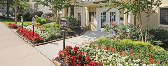 a sidewalk in front of a building with flowers and plants